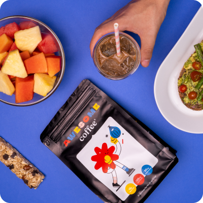 A blue table topped with a bowl of fruit and a bag of awesome coffee