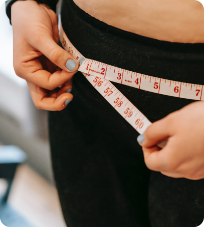 A woman measuring her waist with a measuring tape