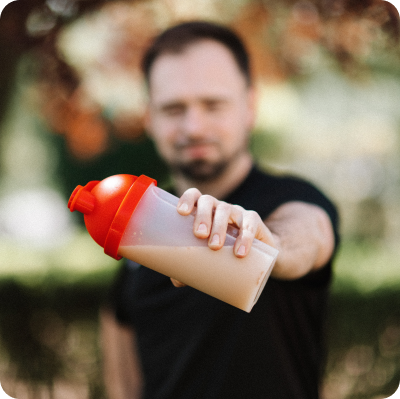 A man holding a bottle with protein coffee in it